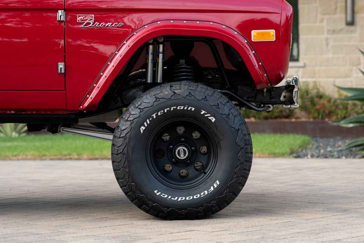 Red 1966 Ford Bronco with BFGoodrich All-Terrain T/A tires on black rims.