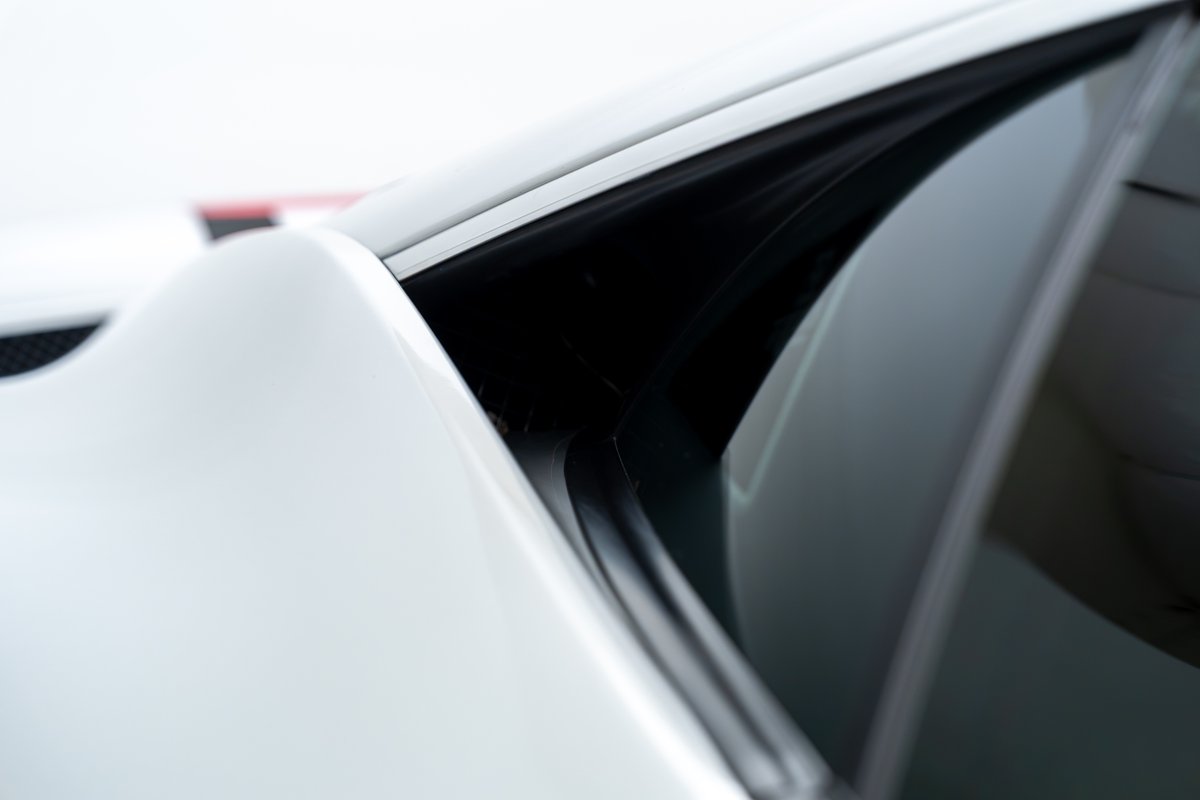 Close-up of the driver's side window trim and body panel on a white 2015 Ferrari 458 Speciale.