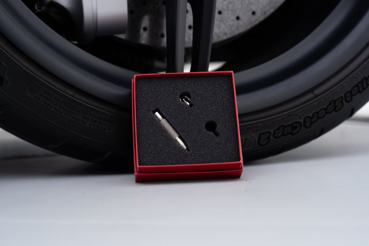2015 Ferrari 458 Speciale tire valve stem tool kit in red box next to wheel.