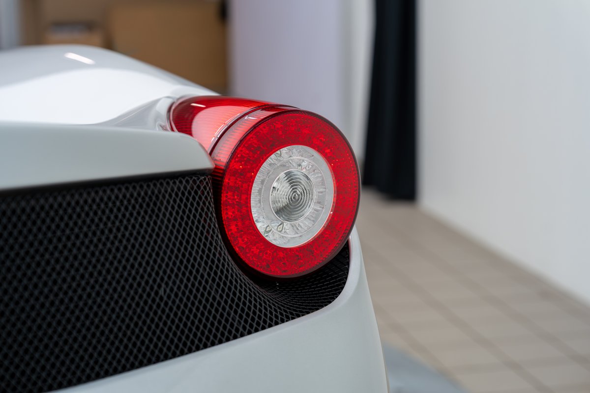 Close-up of the circular taillight and black mesh grille on a white 2015 Ferrari 458 Speciale.