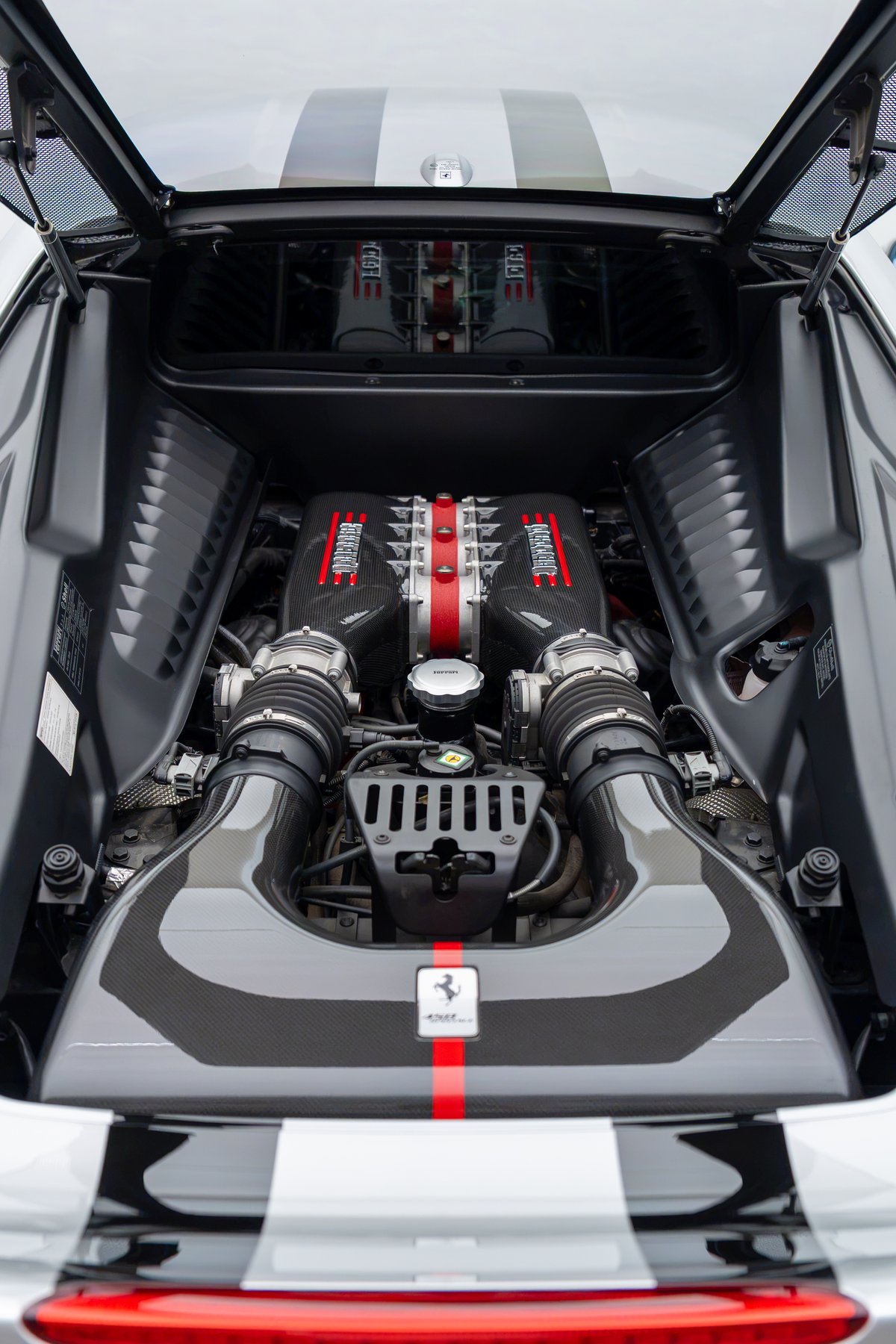 2015 Ferrari 458 Speciale engine bay with carbon fiber intake and red racing stripe livery.