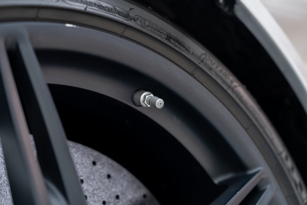 Close-up of a silver valve stem on a matte black rim of a 2015 Ferrari 458 Speciale.