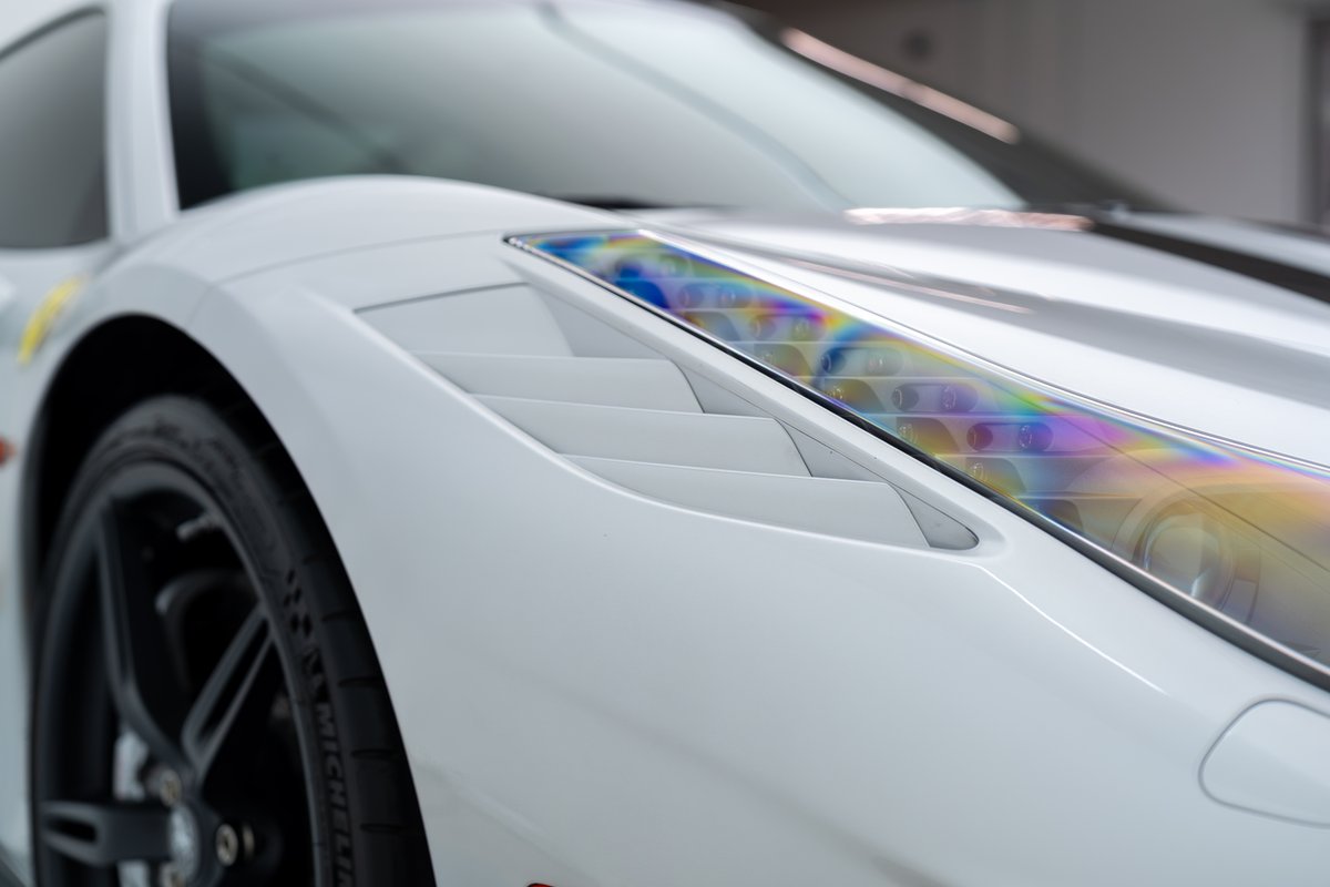 White 2015 Ferrari 458 Speciale with a black race stripe, fender vents, and dark rims.