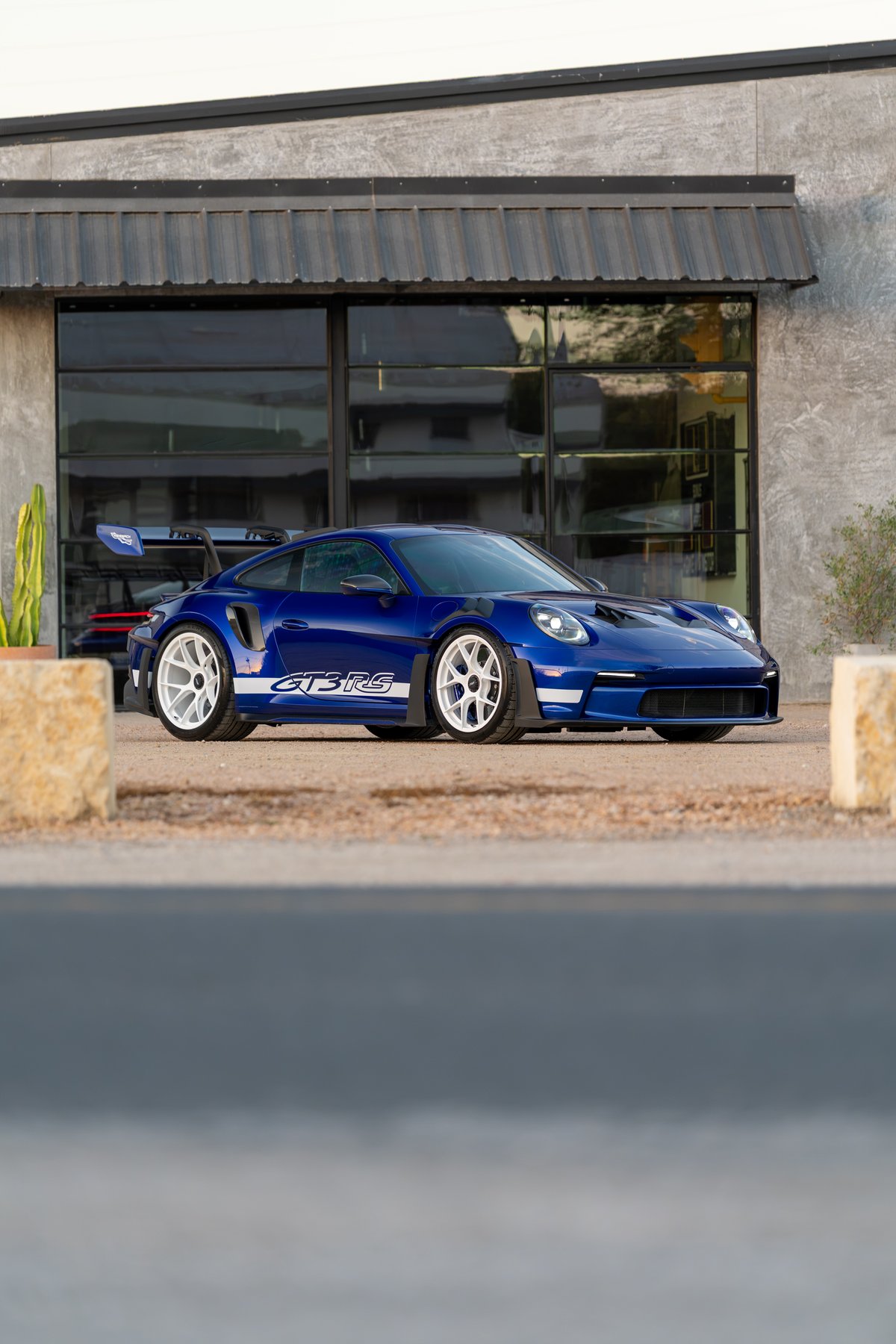 Blue 2025 Porsche 911 GT3 RS with white multi-spoke rims and "GT3 RS" side livery.