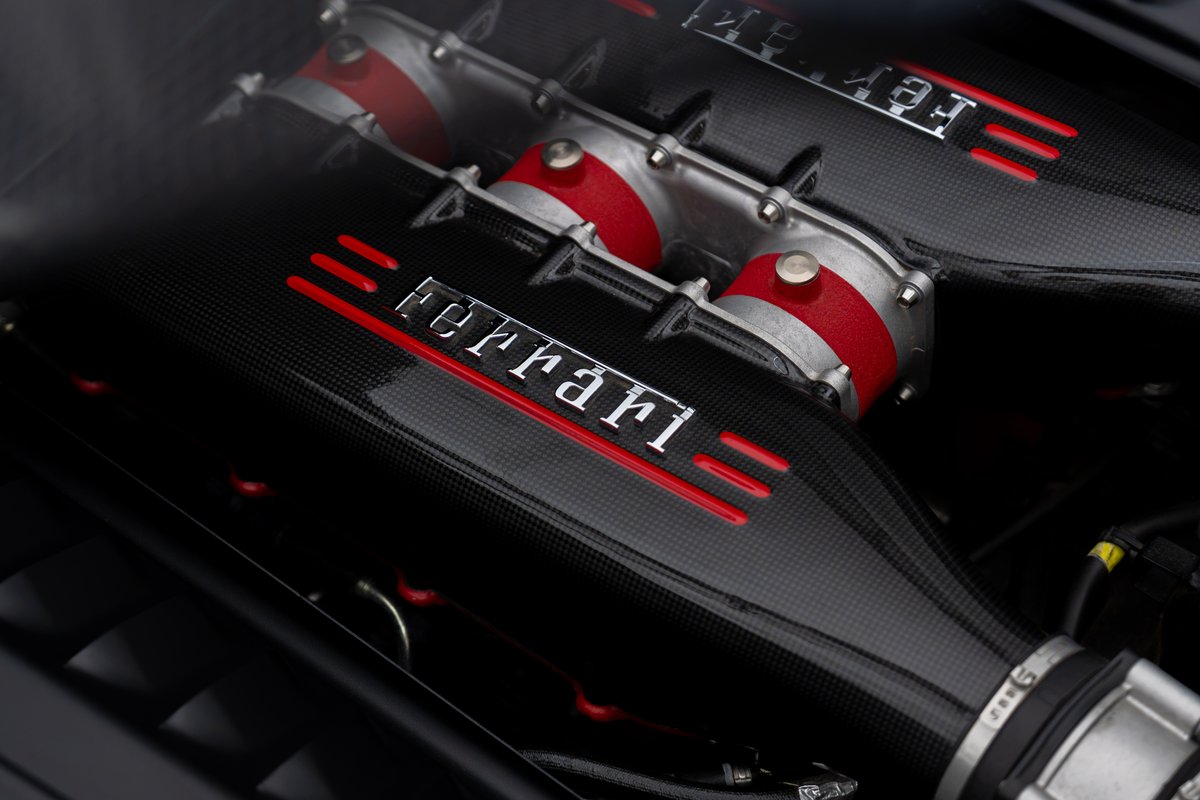 2015 Ferrari 458 Speciale engine bay with carbon fiber intake runners and red trim.