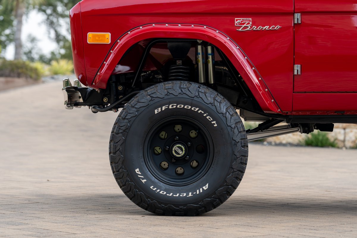 Red 1966 Ford Bronco with BFGoodrich All-Terrain T/A tires on black rims.
