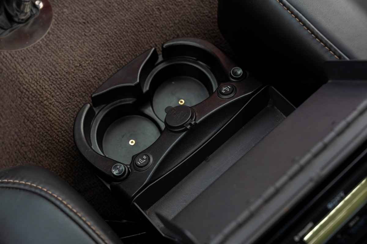 Interior detail: center console cupholders and storage compartment with 12V outlet in a 1966 Ford Bronco.