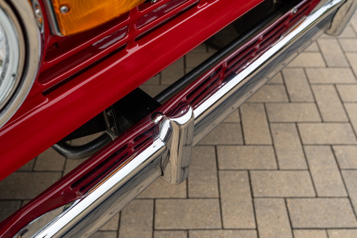 Close-up of a shiny chrome bumper on a red 1966 Ford Bronco.