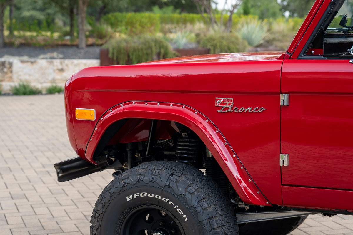 Red 1966 Ford Bronco front fender with "Bronco" emblem and BFGoodrich tire.