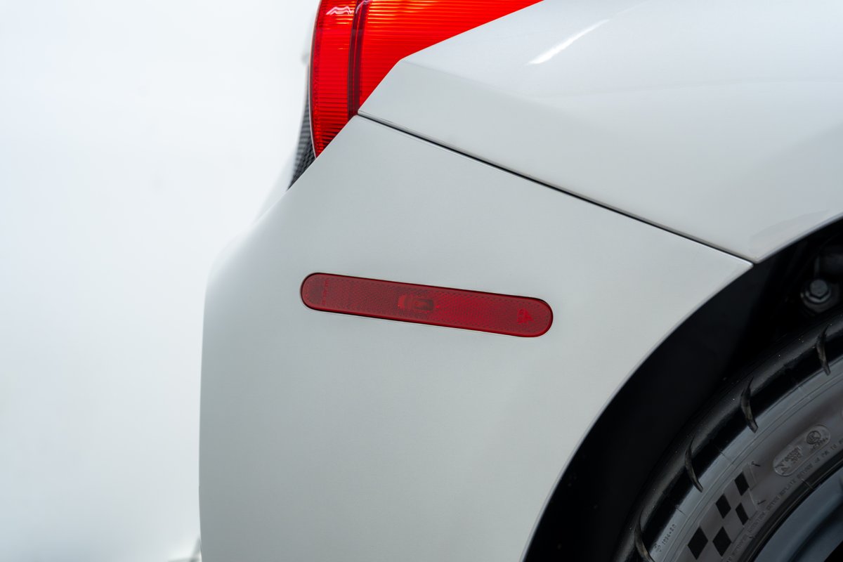Close-up of a white 2015 Ferrari 458 Speciale rear bumper, showing red reflector and tire.