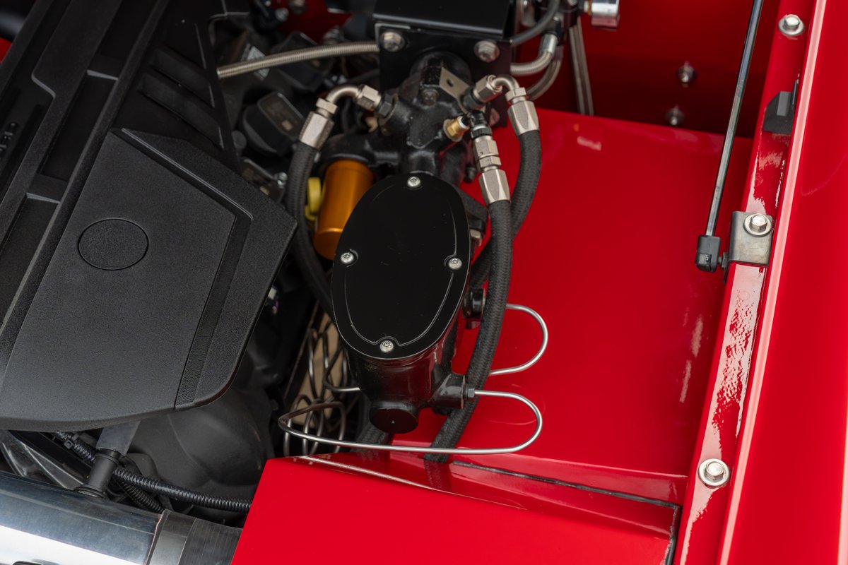 1966 Ford Bronco engine bay with custom brake reservoir and black engine cover.