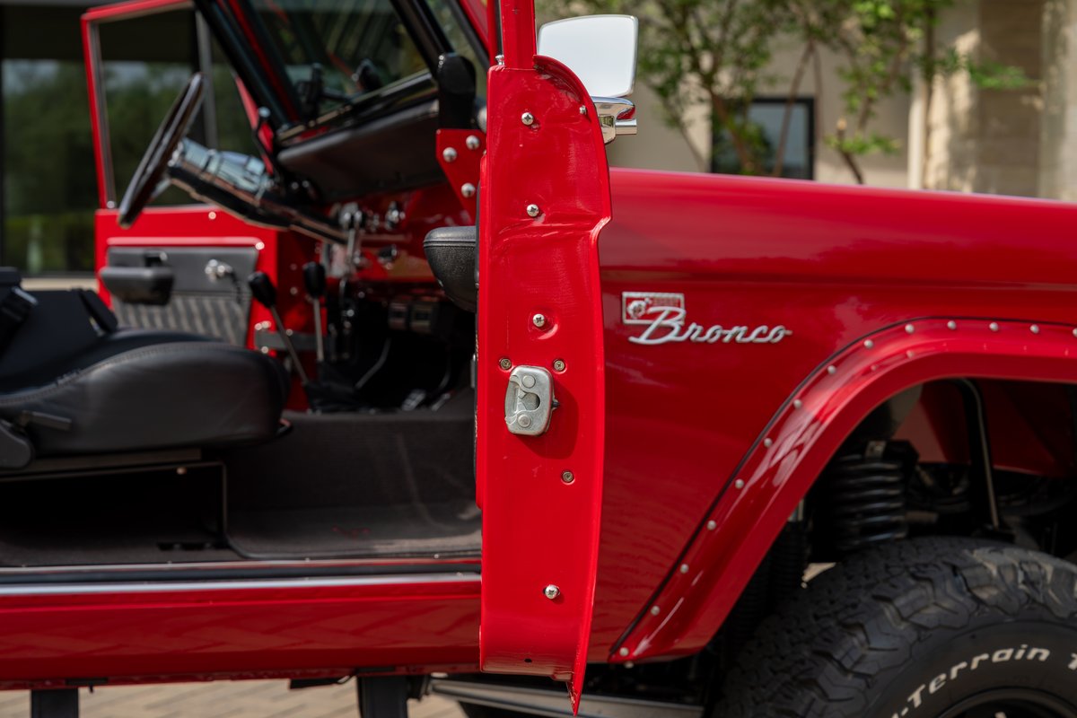 Red 1966 Ford Bronco by Atlas Broncos with chrome trim and fender flares.