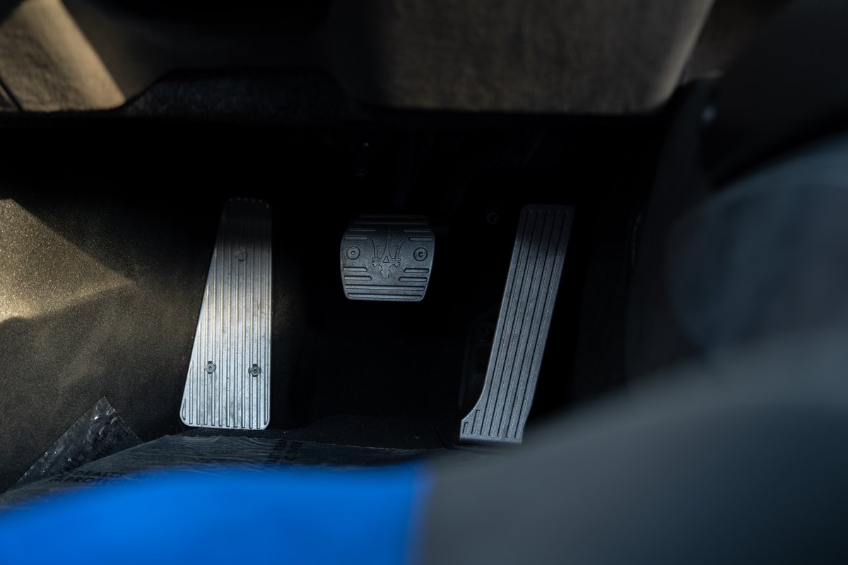 Close-up of the three pedals in a 2024 Maserati MC20, featuring the Trident logo on the clutch.