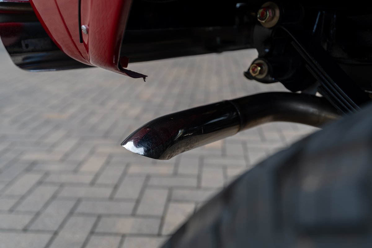 Close up of a chrome exhaust tip on a red 1966 Ford Bronco by Atlas Broncos.