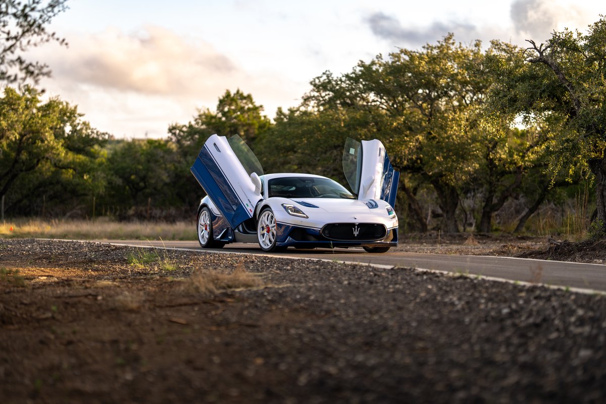 White 2024 Maserati MC20 Icona with blue livery and scissor doors open.