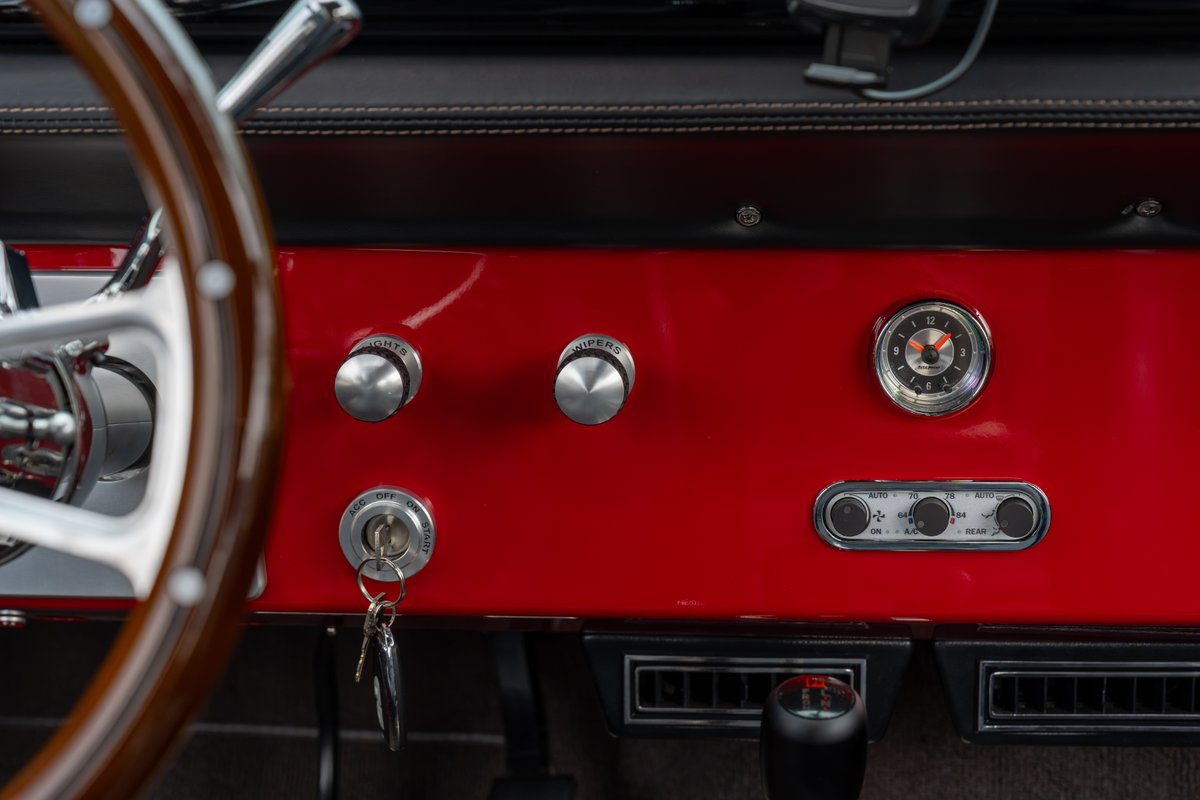 1966 Ford Bronco dashboard: red trim, chrome knobs, vintage clock, wood steering wheel