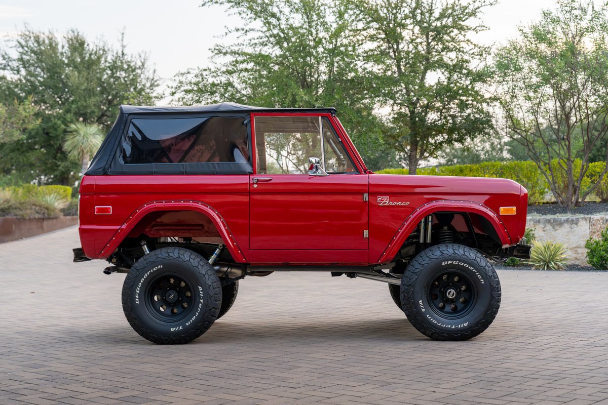 Red 1966 Ford Bronco by Atlas Broncos with black soft top, fender flares, and BFGoodrich All-Terrain tires on black rims.