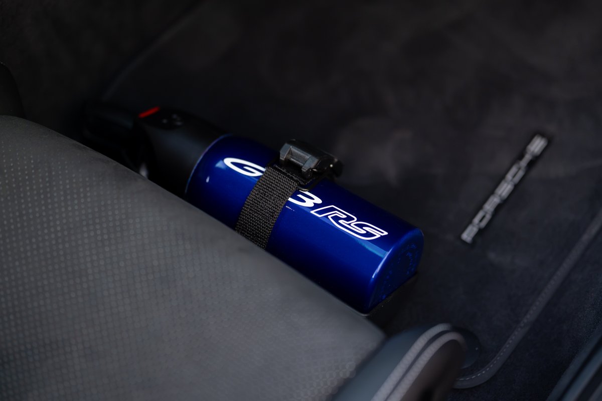 Blue fire extinguisher with "GT3 RS" livery secured to the seat of a Porsche 911 GT3 RS.