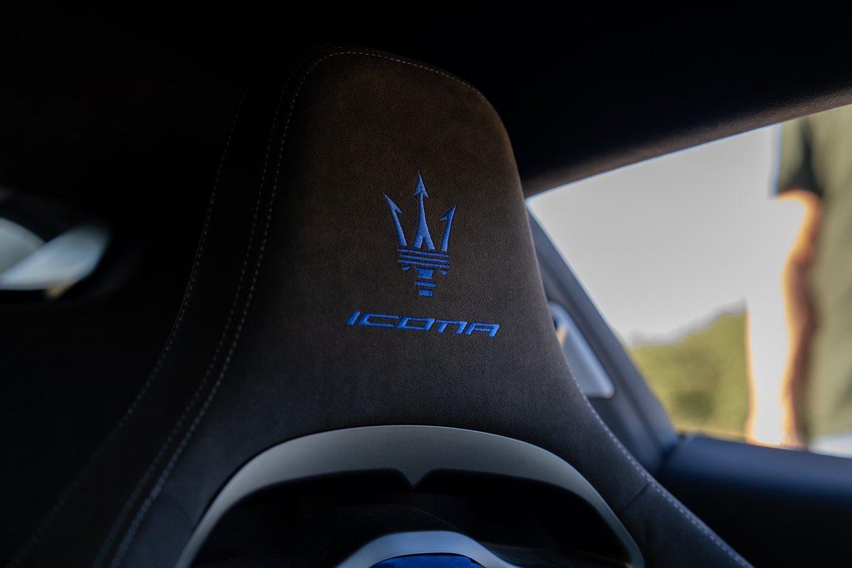 Maserati MC20 Icona interior detail: blue Trident logo embroidered on dark suede seat trim with contrasting stitching.