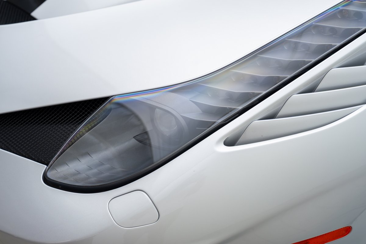 Close-up of a white 2015 Ferrari 458 Speciale's sharp LED headlight and aggressive side air intake.