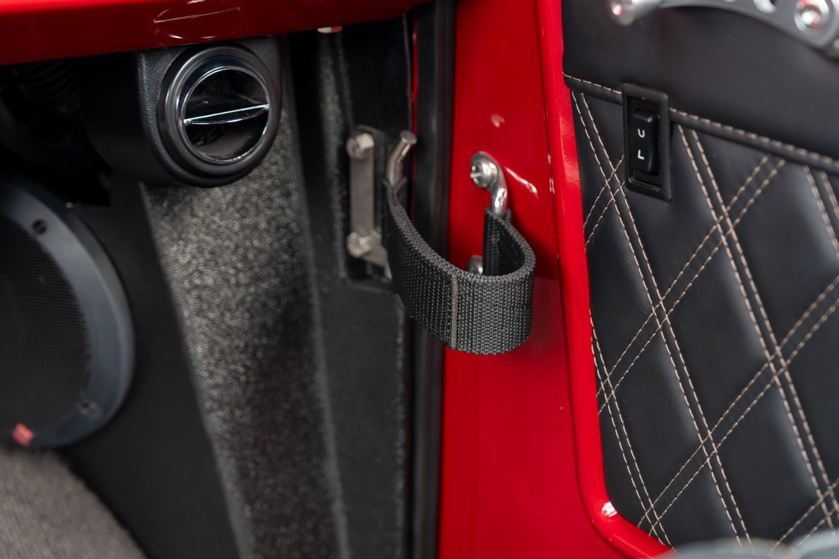1966 Ford Bronco interior: red door, black diamond-stitched trim, speaker, air vent.
