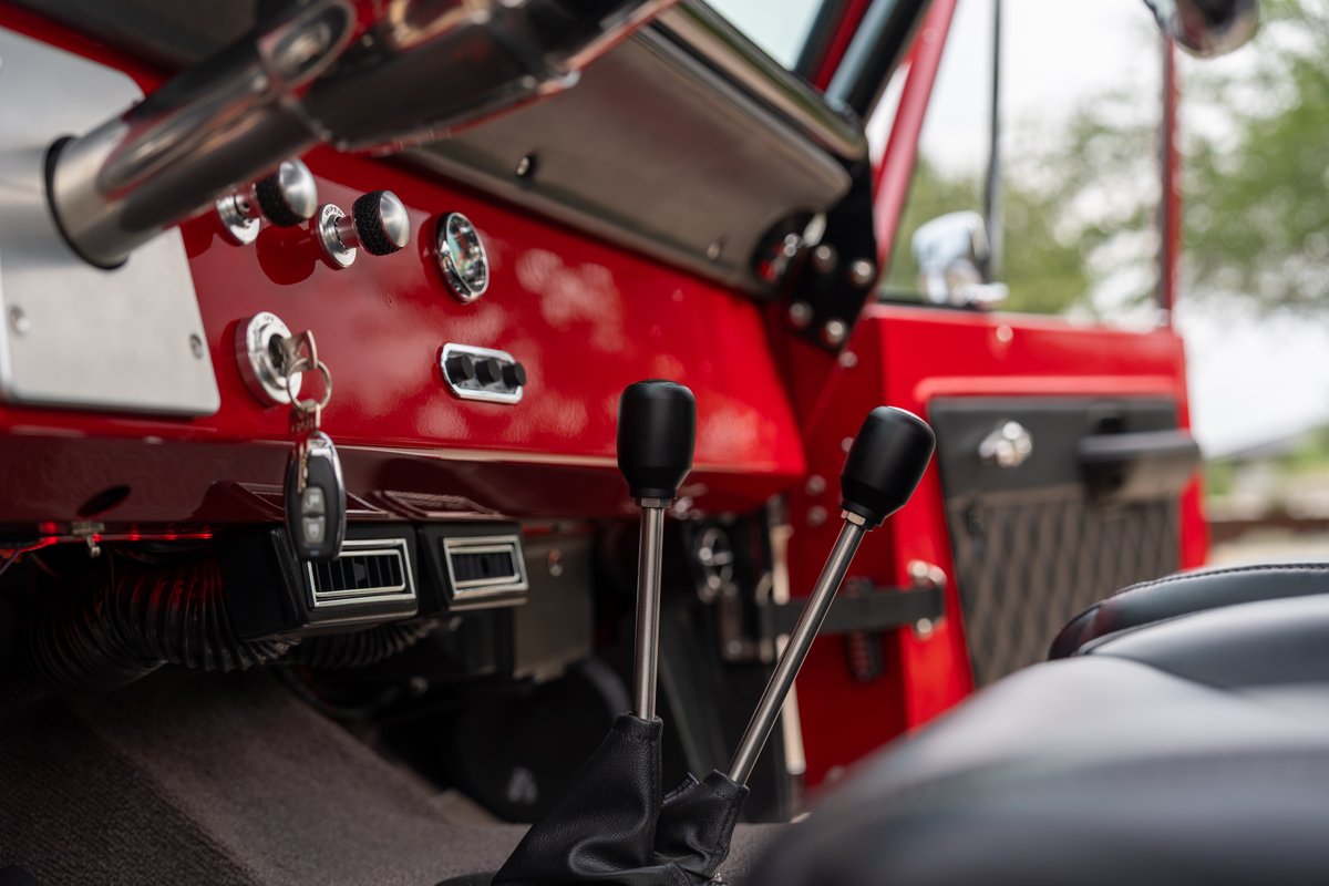 1966 red Ford Bronco interior: two shifters, vents, ignition key.
