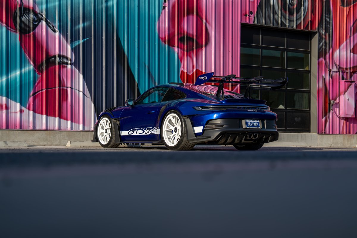 Blue 2025 Porsche 911 GT3 RS with white multi-spoke rims and "GT3 RS" livery.