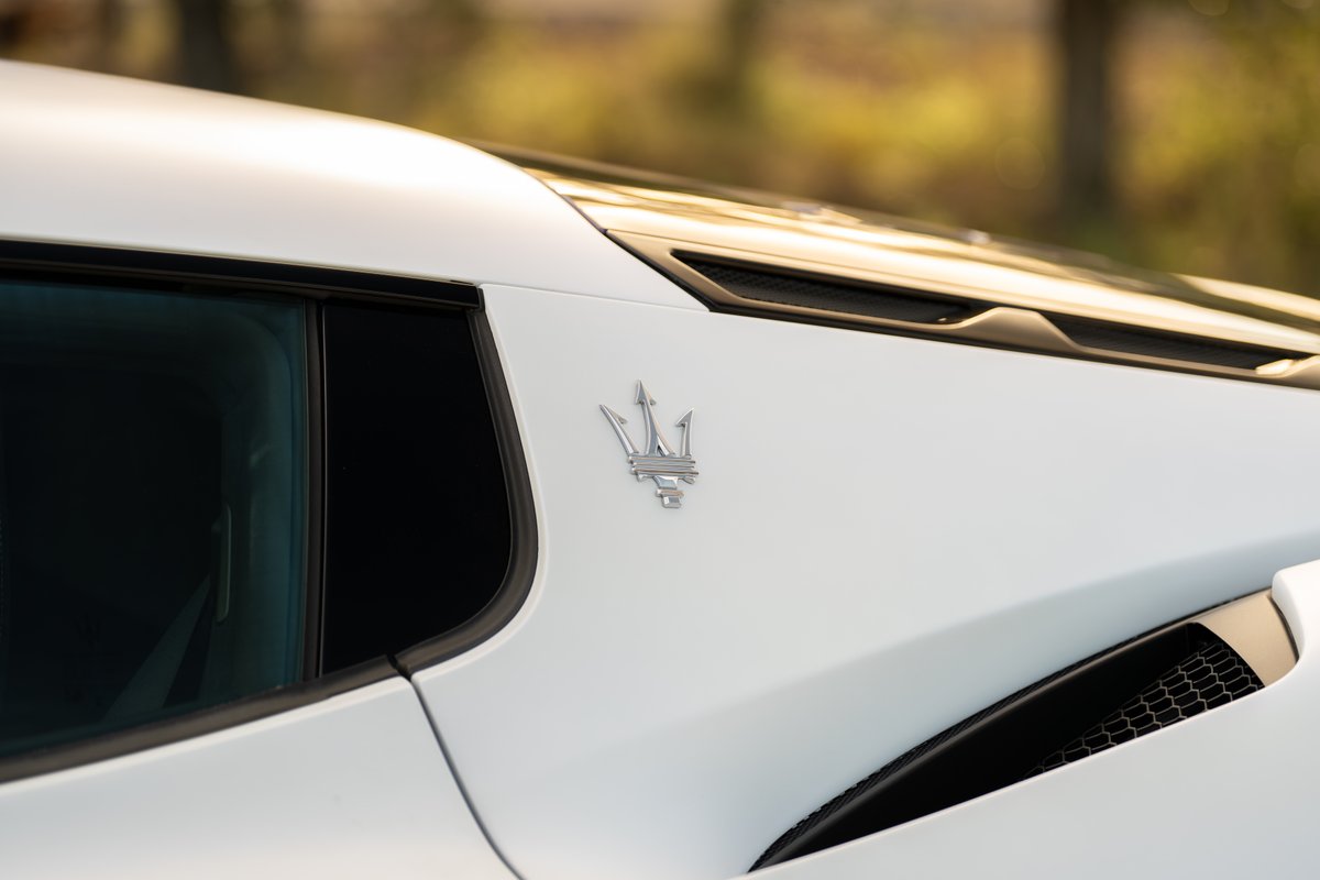White 2024 Maserati MC20 Icona with iconic trident emblem on body trim.