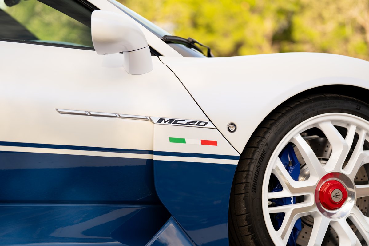 White 2024 Maserati MC20 Icona with blue stripes, "MC20" badging, Italian flag livery, and white rims with blue brake calipers.