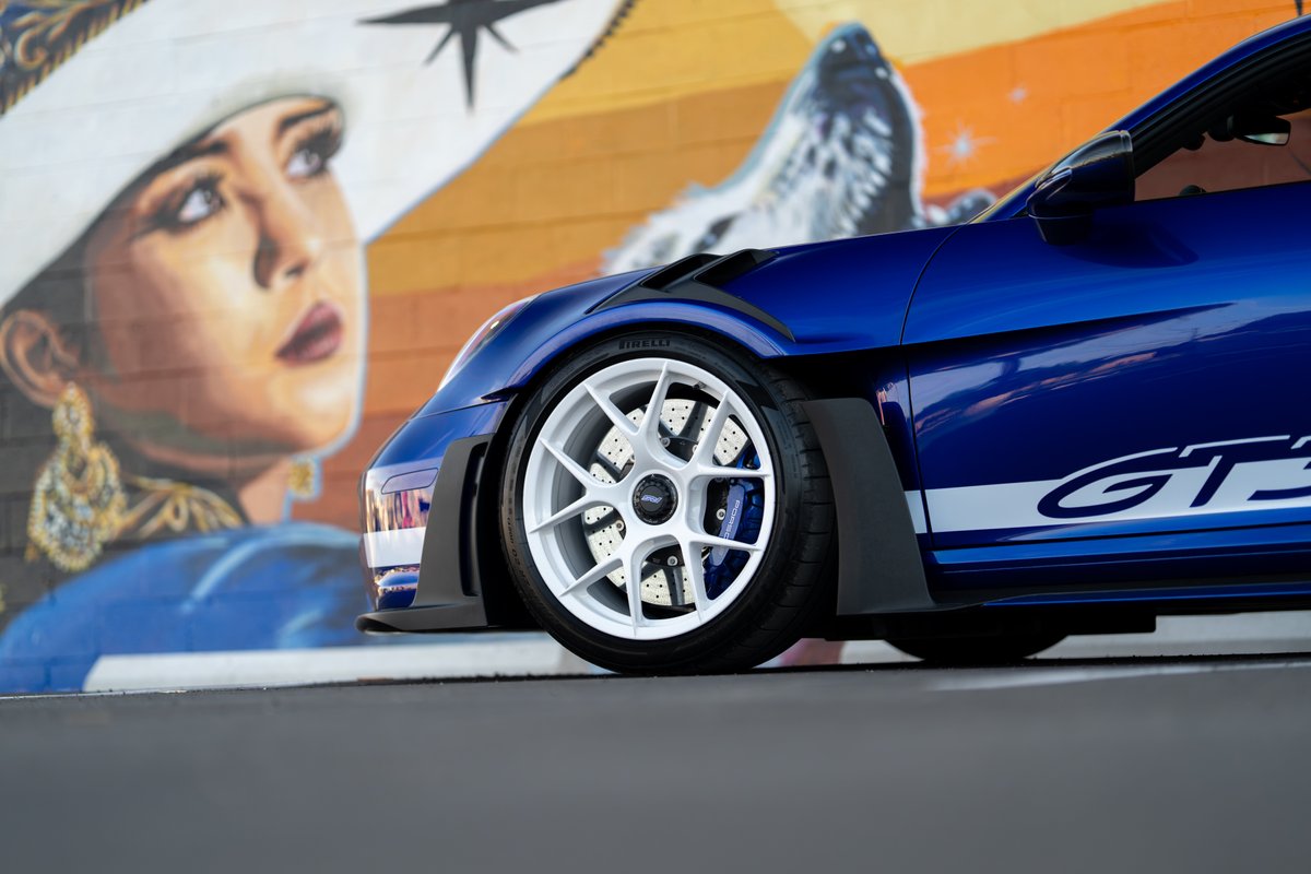 2025 Porsche 911 GT3 RS in blue with white racing stripes and white rims.