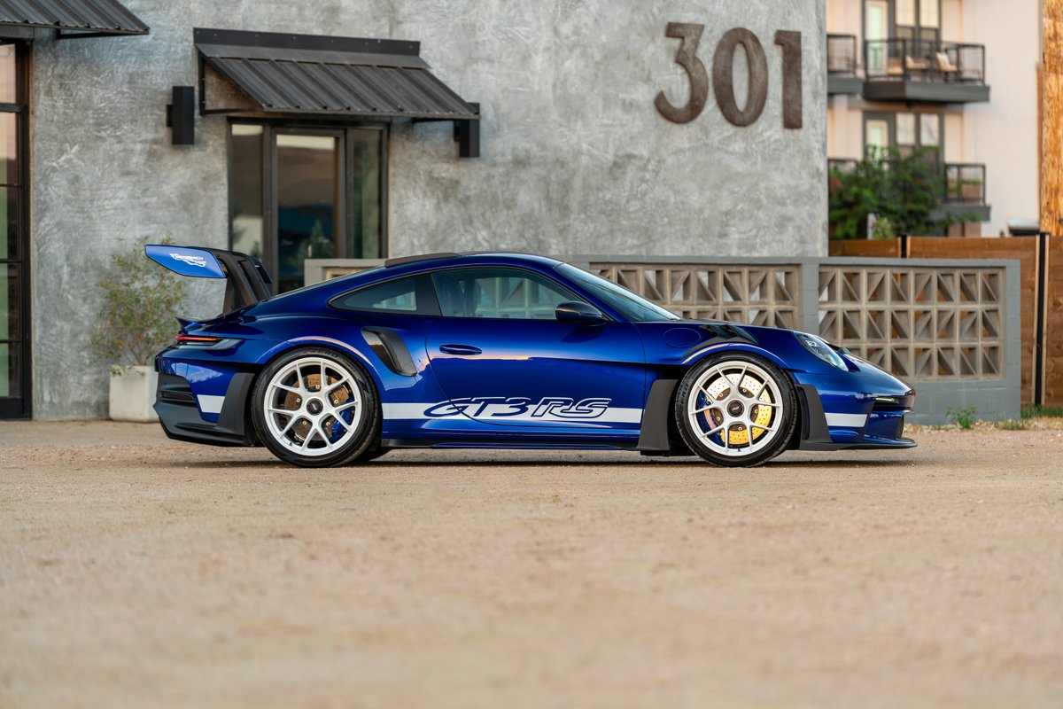 Blue 2025 Porsche 911 GT3 RS with white "GT3 RS" livery and white rims.