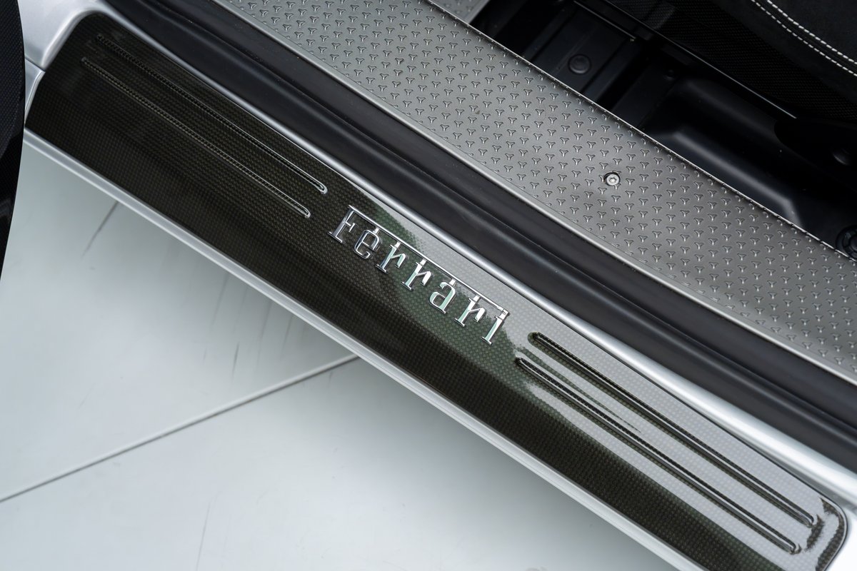 Close-up of carbon fiber door sill trim with "Ferrari" script on a 2015 Ferrari 458 Speciale.