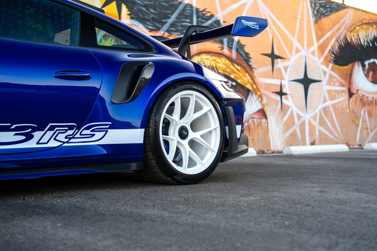 2025 Porsche 911 GT3 RS in blue with white livery and white rims, featuring a large rear wing.