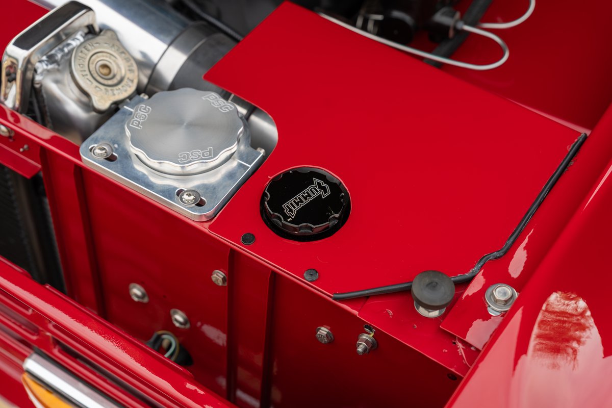 Close-up of the engine bay of a red 1966 Ford Bronco, showing custom caps.