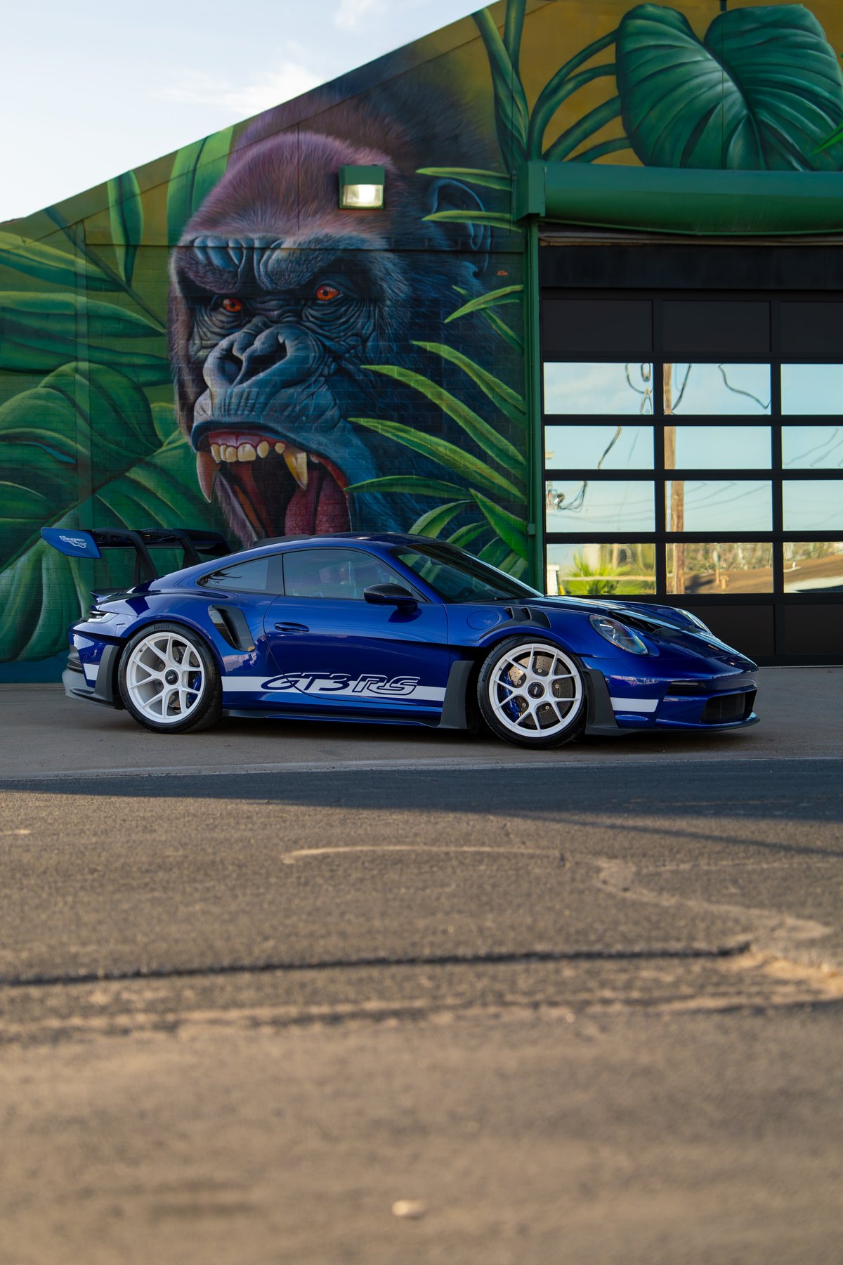 2025 Porsche 911 GT3 RS in blue with white racing livery and white rims.