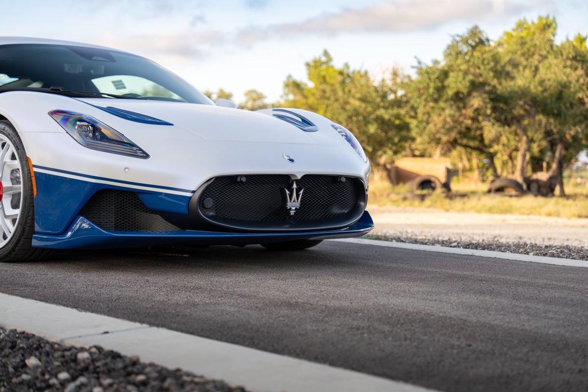 Front view of a white and blue 2024 Maserati MC20 Icona, showcasing its grille and headlights.