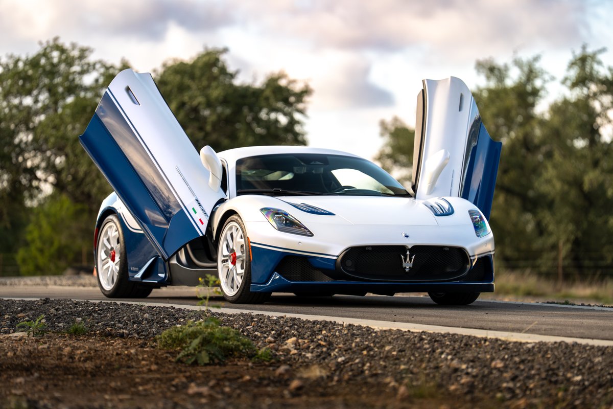 White 2024 Maserati MC20 Icona with blue livery and scissor doors open.