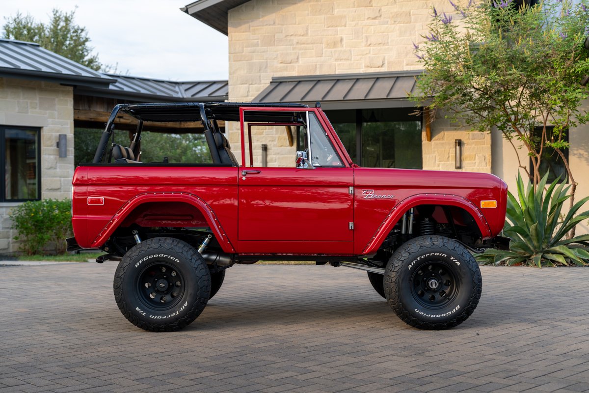 1966 red Ford Bronco by Atlas Broncos with black roll cage, BFGoodrich All-Terrain tires, and black rims.