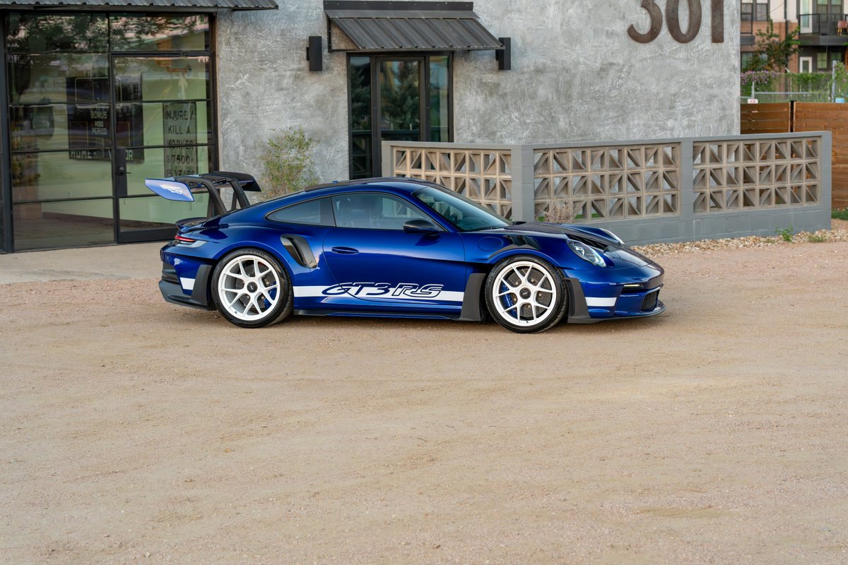A blue 2025 Porsche 911 GT3 RS with white rims and GT3 RS livery.