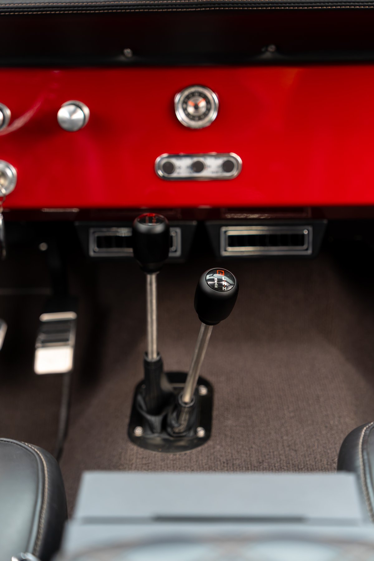 1966 Ford Bronco with red dash, two shifters, and black seats.