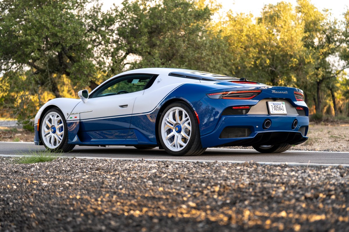Rear 3/4 view of a 2024 Maserati MC20 Icona in blue and white livery, white rims.