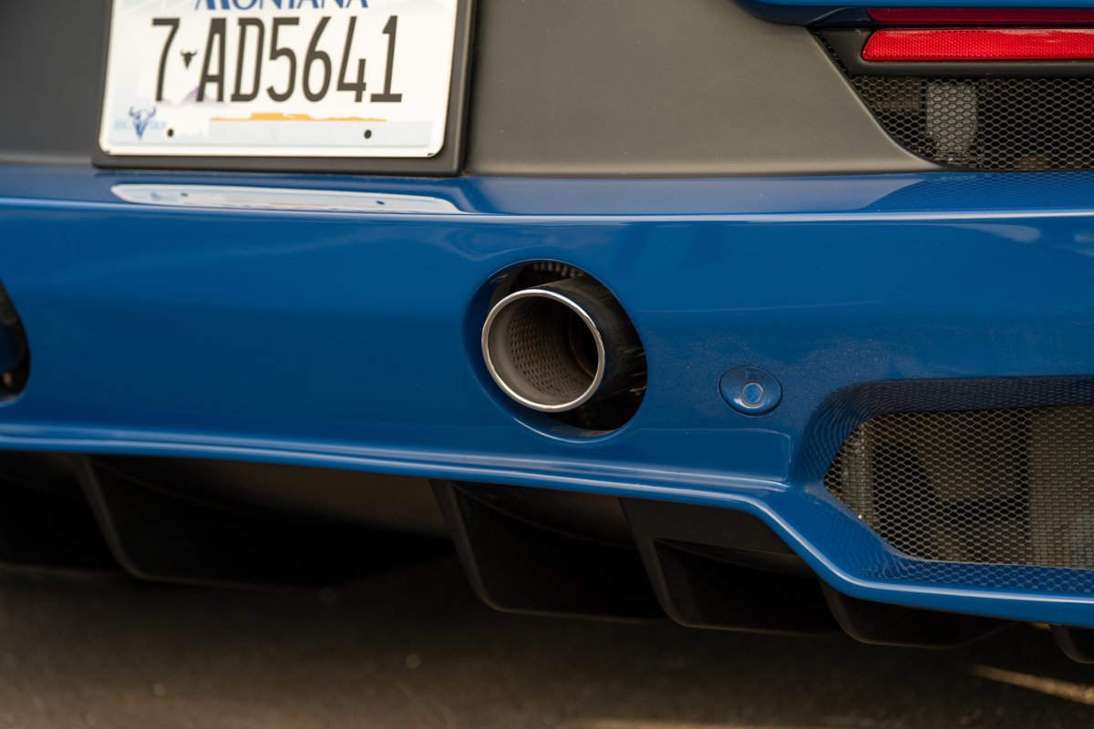 Close-up of the polished exhaust tip and rear diffuser on a blue 2024 Maserati MC20 Icona.