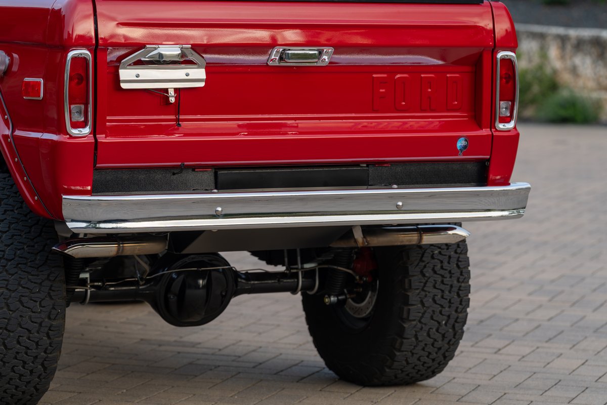 Rear view of a red 1966 Ford Bronco by Atlas Broncos, showing chrome bumper & exhaust.
