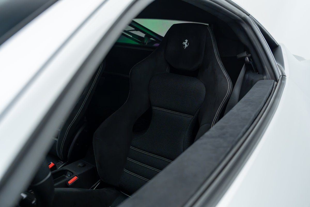 Interior shot of the 2015 Ferrari 458 Speciale's black Alcantara racing seat with white stitching and embossed Prancing Horse logo.