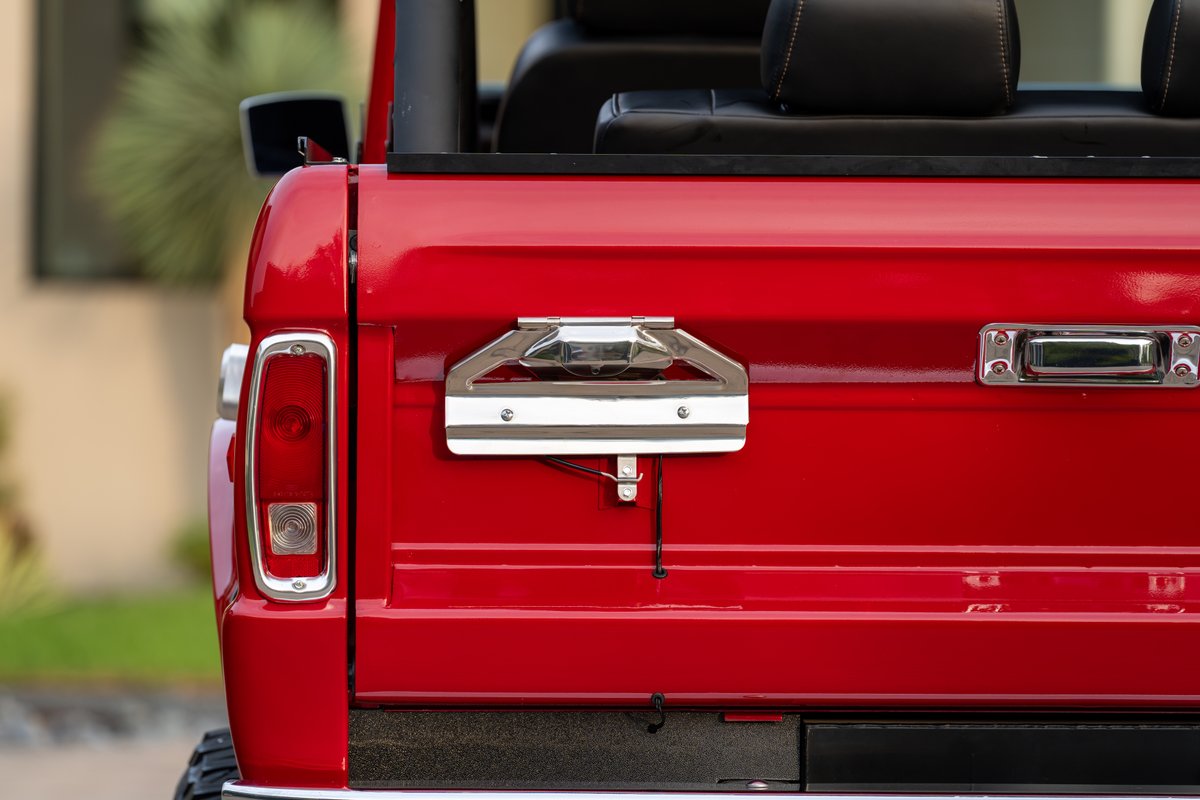 Red 1966 Ford Bronco by Atlas Broncos, rear view, chrome tailgate handle, taillight, and trim.