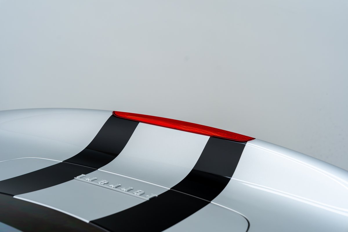 Silver 2015 Ferrari 458 Speciale with black racing stripes and a red brake light.
