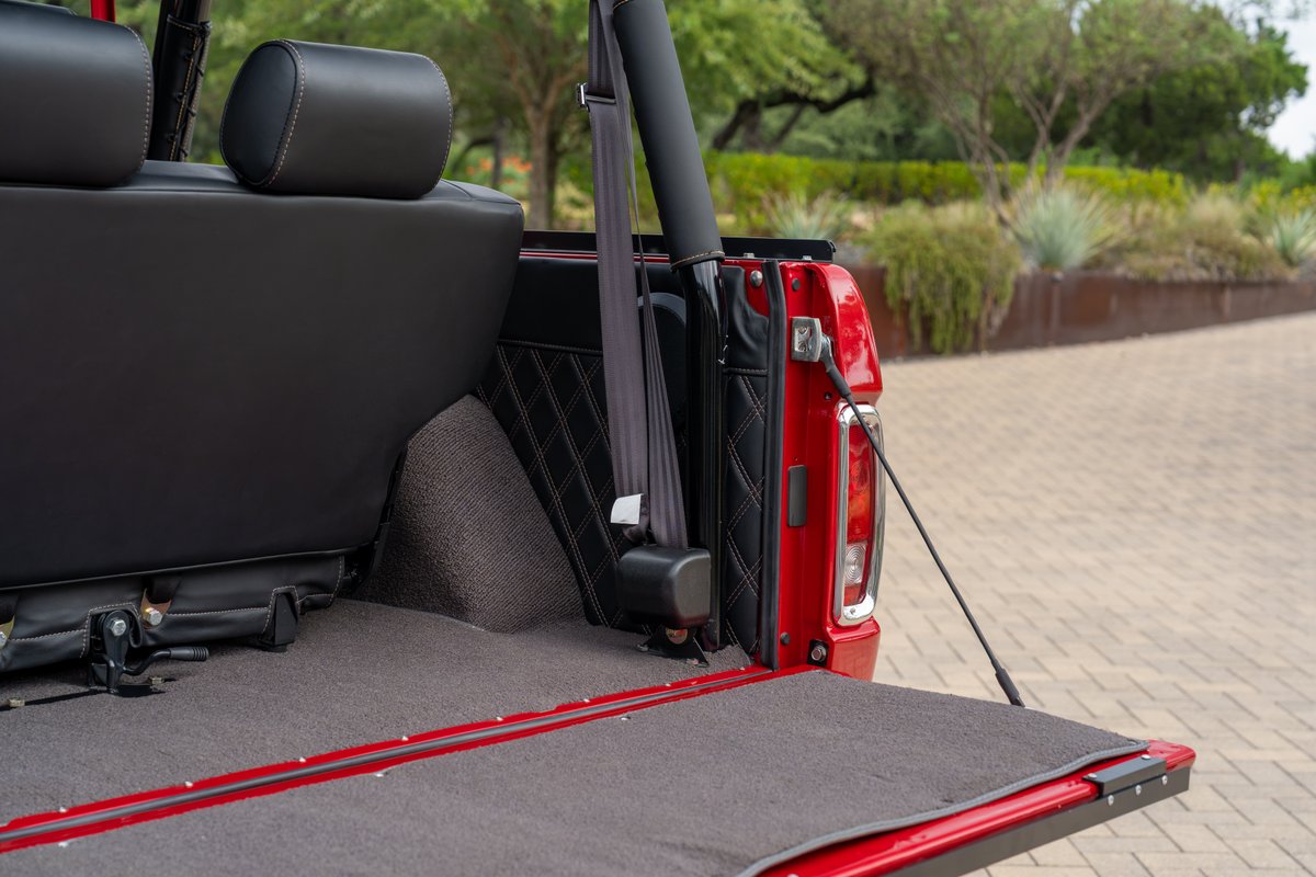 Red 1966 Ford Bronco with diamond-stitched interior trim and plush carpet.