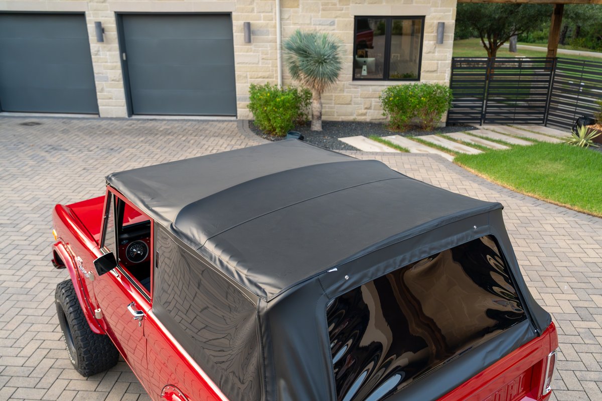 Red 1966 Ford Bronco by Atlas Broncos with a black soft top and large off-road tires.