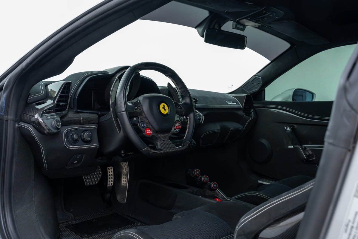 Interior view of a 2015 Ferrari 458 Speciale, featuring carbon fiber trim, Alcantara seats, and a racing steering wheel.