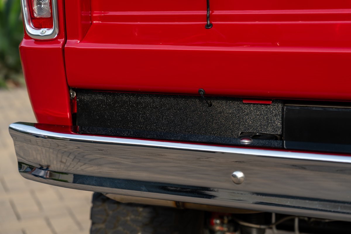 Close-up of red 1966 Ford Bronco rear bumper and tailgate trim.